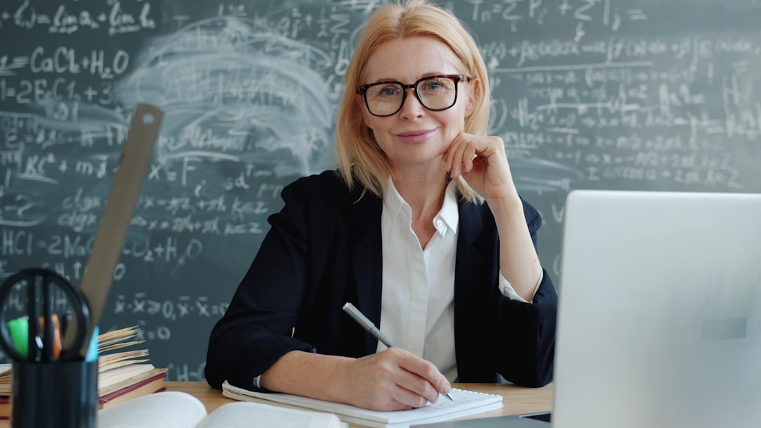 Profesora sonriendo en su escritorio con un ordenador portátil